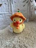 Crocheted duck toy with a tag on a textured surface