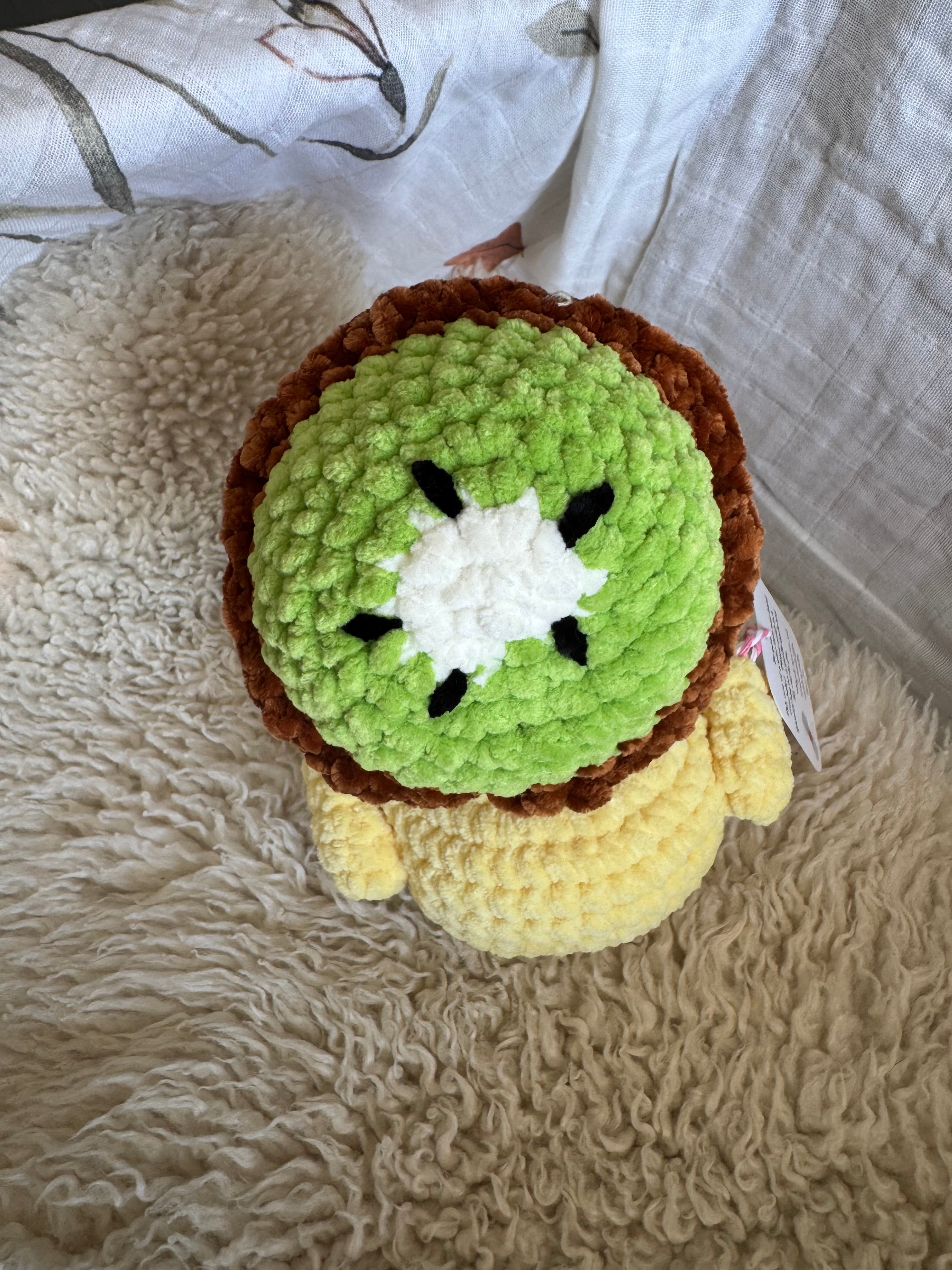 Crocheted duck with kiwi hat plush toy on a textured surface