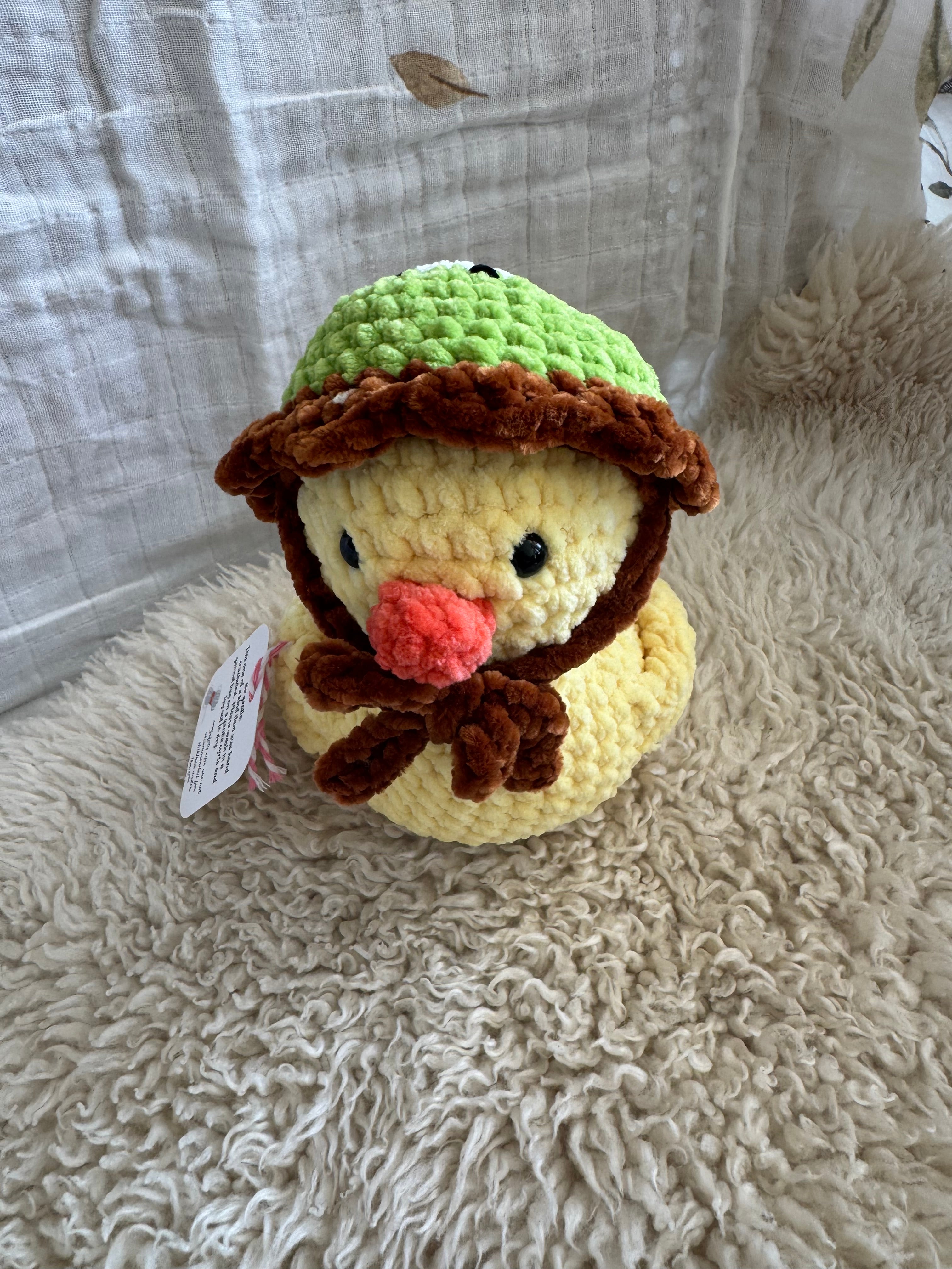 Crocheted duck plush toy on a textured surface
