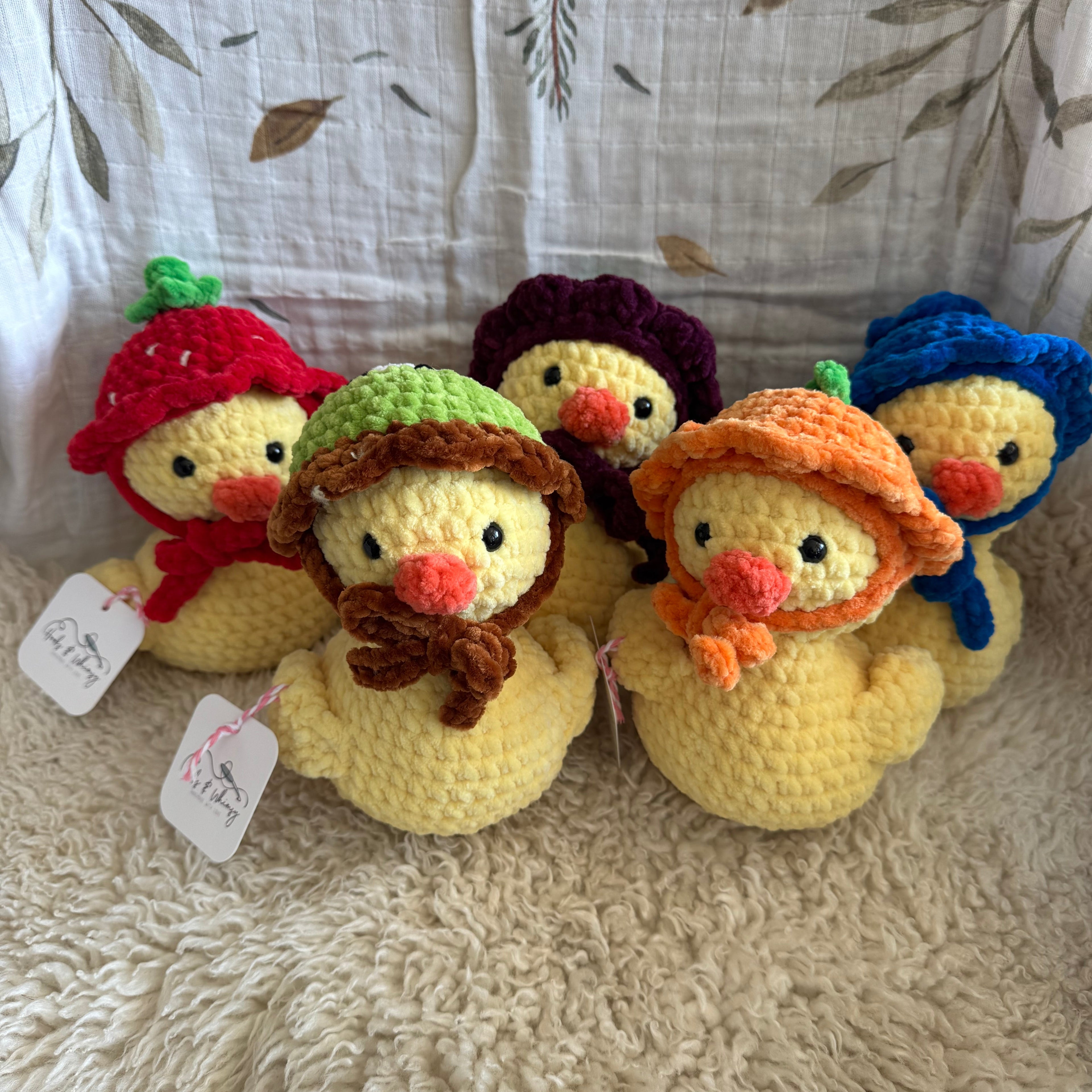 Stack of colorful crochet duck toys on a textured surface