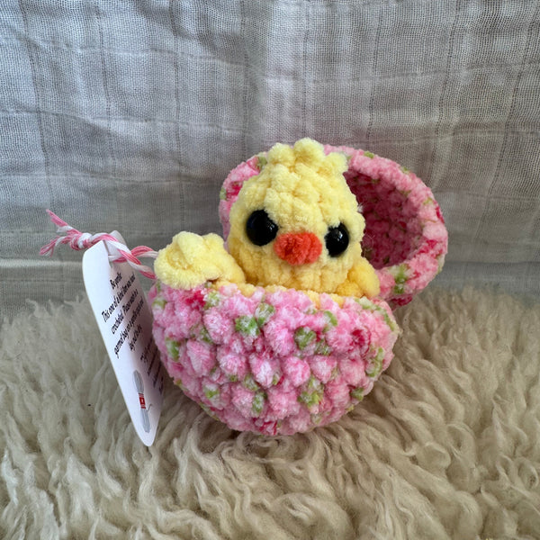 Crocheted egg with a chick design on a textured surface