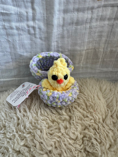 Crocheted chick pop up toy on a textured fabric background