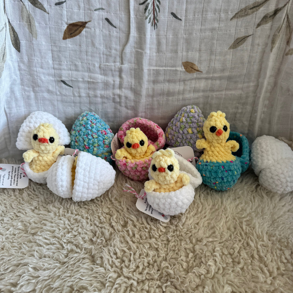 Crocheted animal toys hanging on a textured surface with a leaf-patterned fabric background.