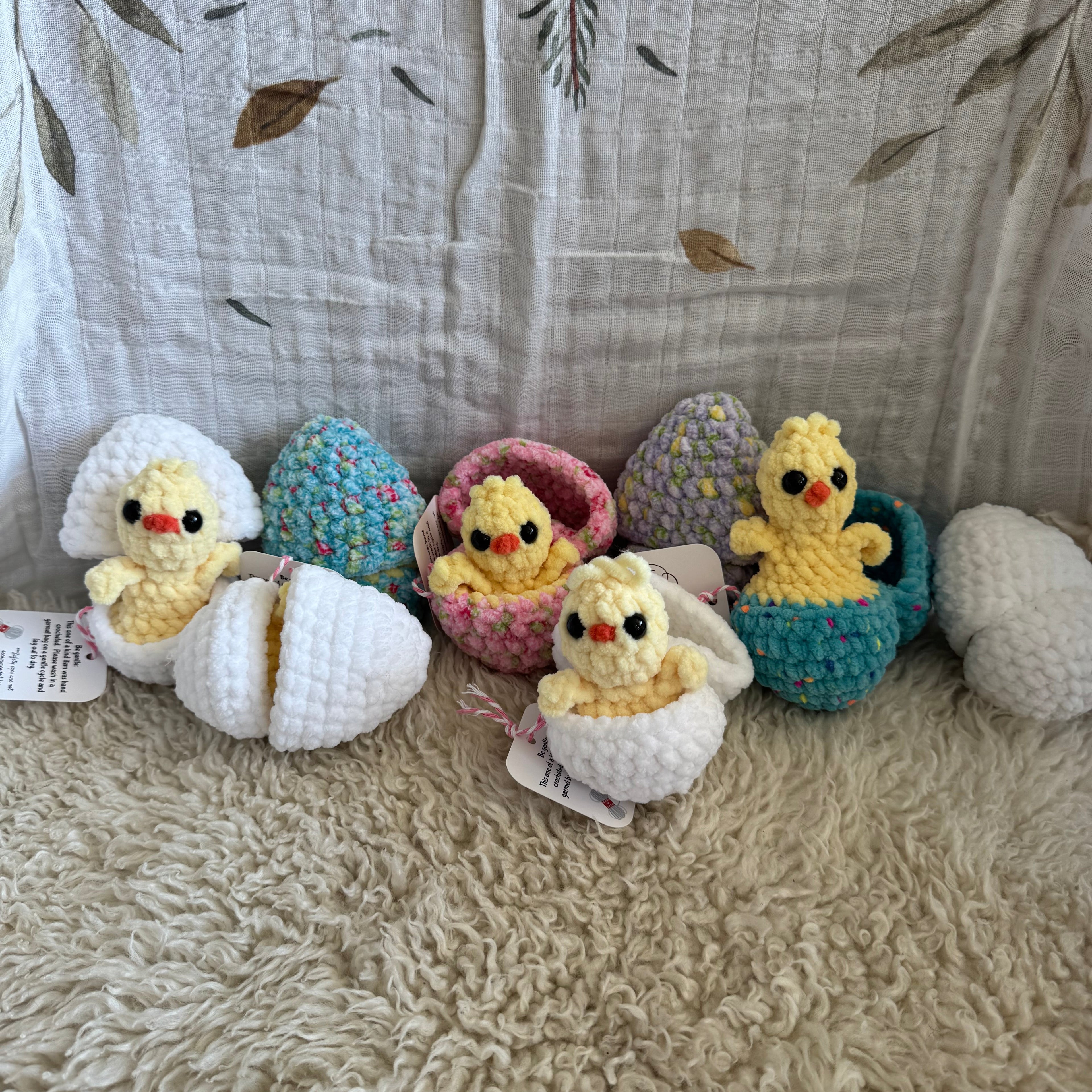 Crocheted animal toys hanging on a textured surface with a leaf-patterned fabric background.