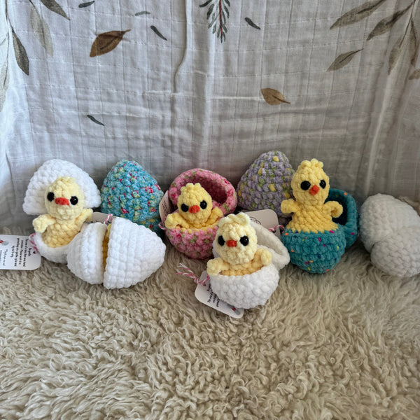 Crocheted animal toys hanging on a textured surface with a leaf-patterned fabric background.