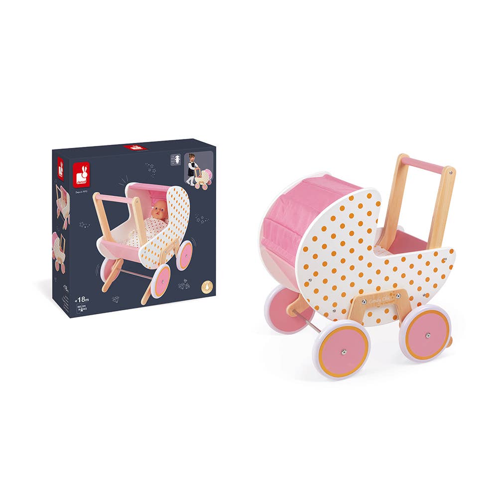 A wooden baby stroller toy shown next to its dark navy blue retail box. The stroller features a pink canopy, a white side panel with orange polka dots, natural wood frame and handle, and pink wheels with orange-rimmed centers.