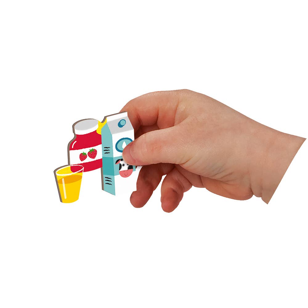 Hand holding a small colorful model of a milk carton with a glass and a can on a white background