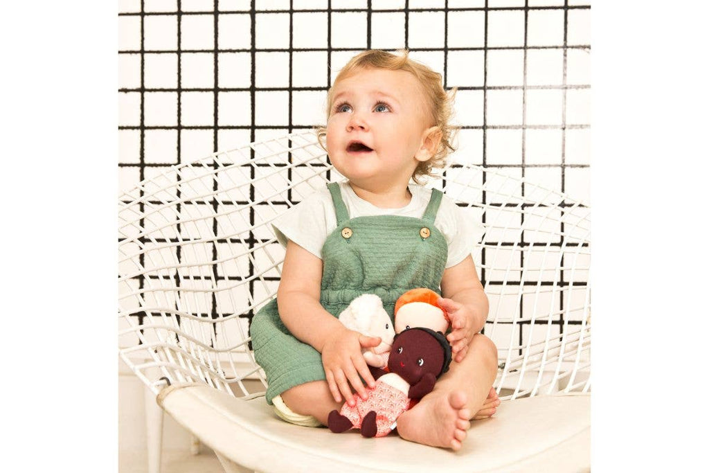 Child sitting on a white chair holding plush toys against a black and white grid background