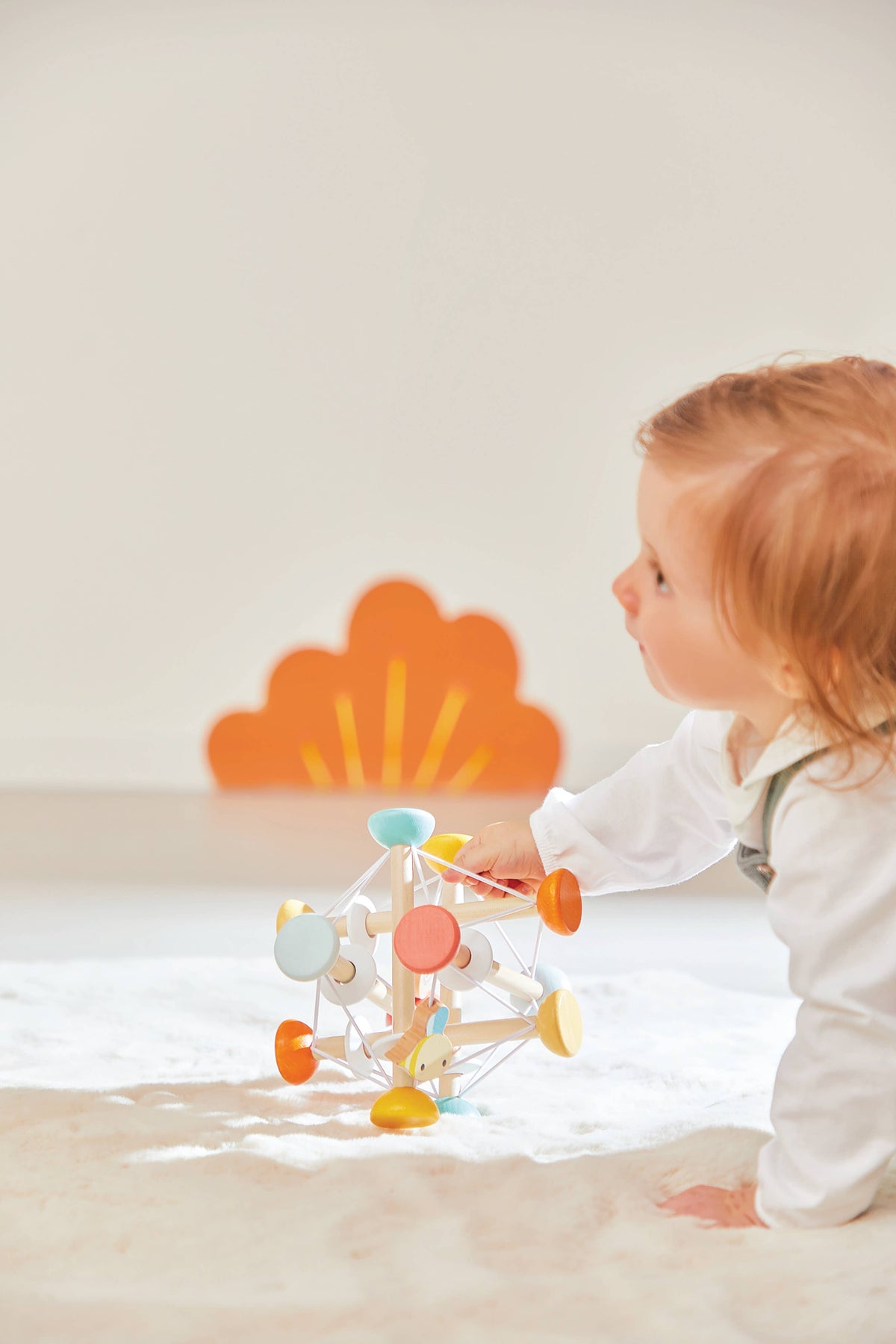 Child playing with a colorful wooden toy on a light surface.