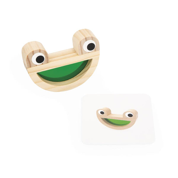 Wooden toy with googly eyes and a green mouth on a white background