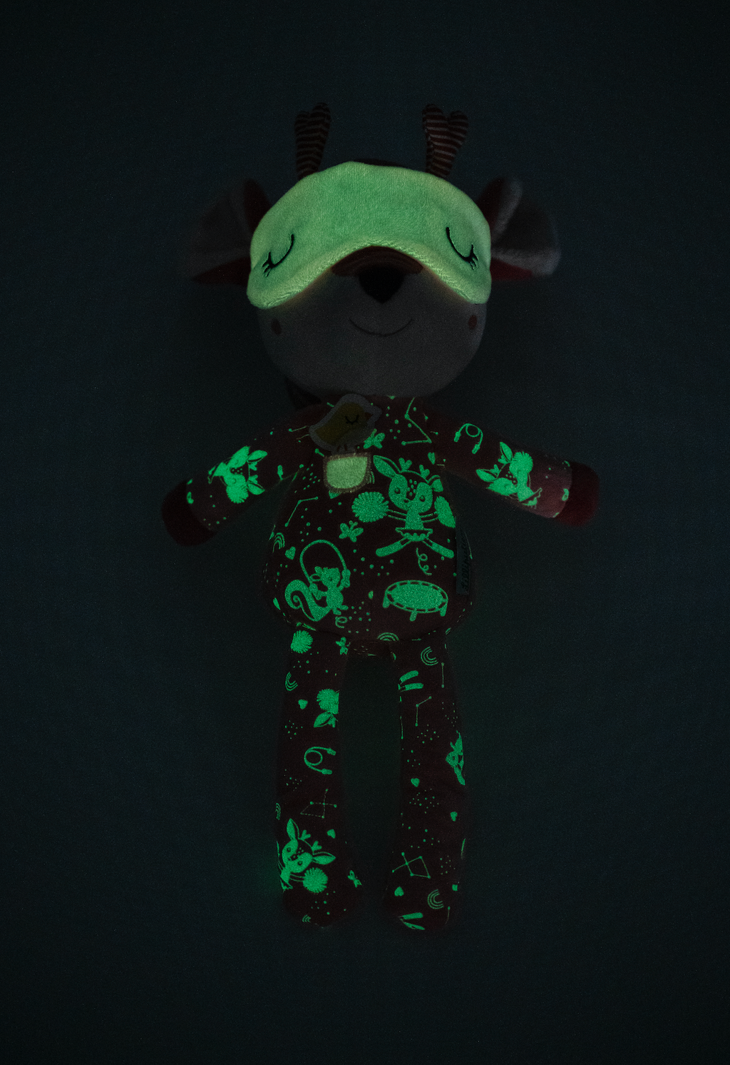 Glowing plush toy with green patterns on a black background