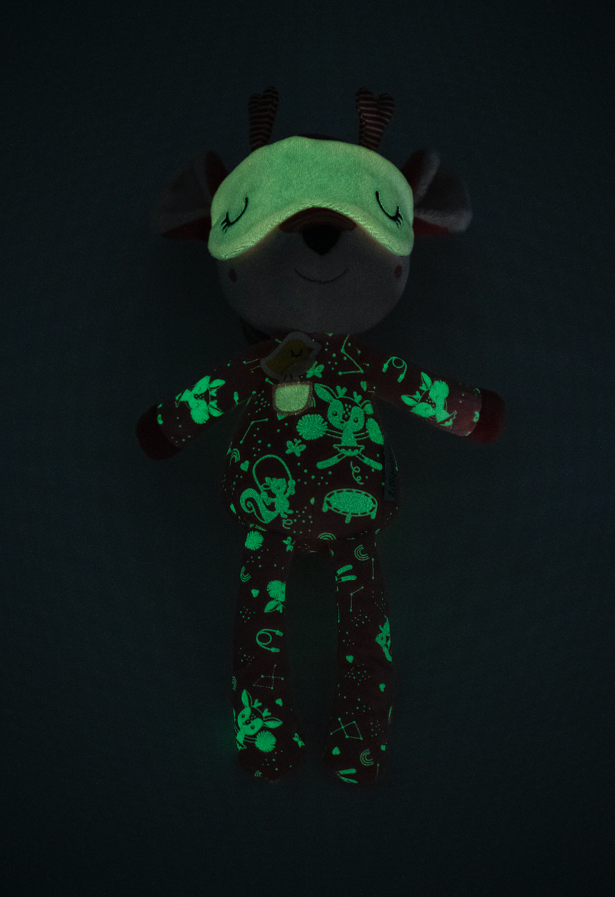 Glowing plush toy with green patterns on a black background