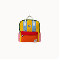 A colorful striped backpack made from textured fabric panels in yellow, blue, green, red, orange, and pink, with white top handles and small brand patches on the front, shown against a plain white background.
