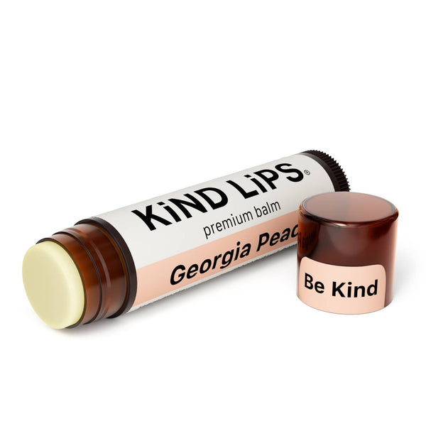 Lip balm tube labeled 'Kind Lips' with a small container labeled 'Be Kind' on a white background.