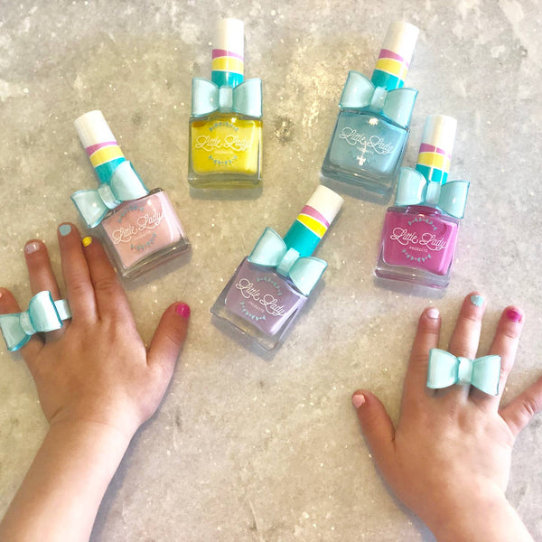 Set of colorful nail polish bottles with matching bow-shaped rings on a neutral background