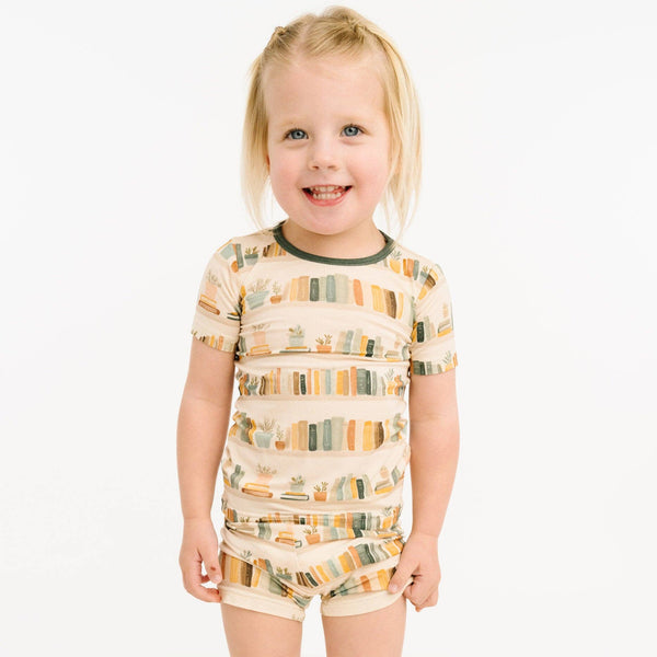 Child wearing a patterned shirt and shorts set on a white background