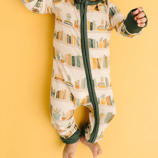 Baby wearing a onesie with book design on a yellow background