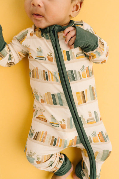 Baby wearing a patterned onesie with a zipper on a yellow background