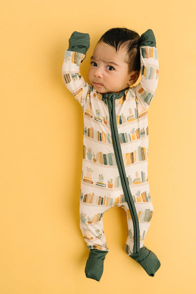 Baby in a patterned onesie with green accents on a yellow background