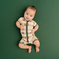 Baby wearing a patterned onesie on a green background