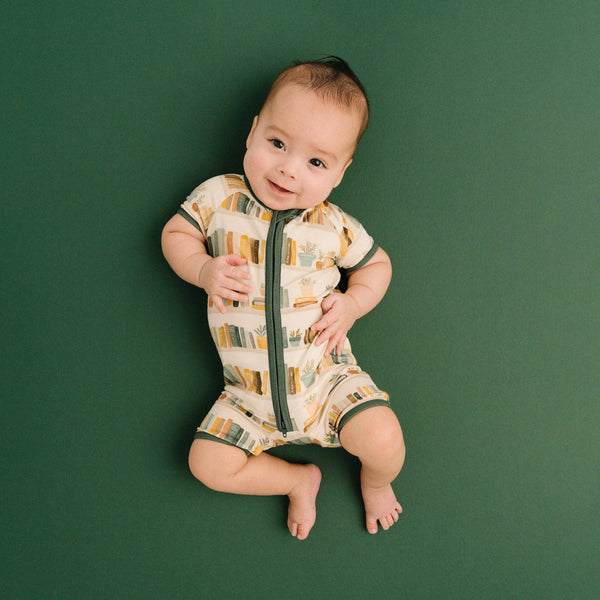 Baby wearing a patterned onesie on a green background