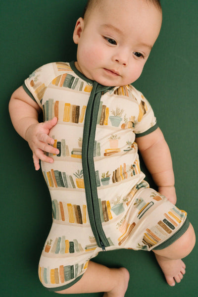 Baby wearing a patterned onesie on a green background
