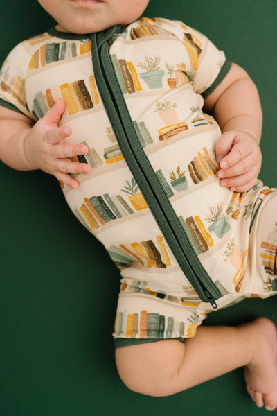 Baby wearing a patterned onesie with a green background
