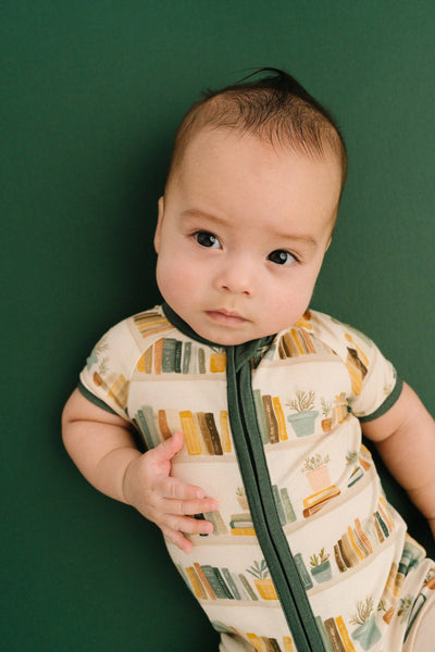Baby wearing a patterned onesie against a green background