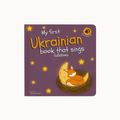 My first Ukrainian book that sings lullabies children's book with a purple cover, featuring yellow stars and an illustration of an orange fox sleeping in a nest on a crescent moon.