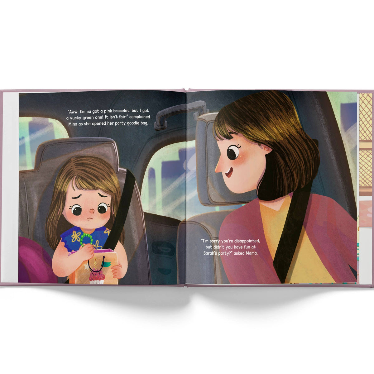 An open children's picture book showing a illustrated scene inside a car with a young girl in the seatbelt holding a pink phone and a woman beside her. The pages have black text bubbles and a light gray background around the book.
