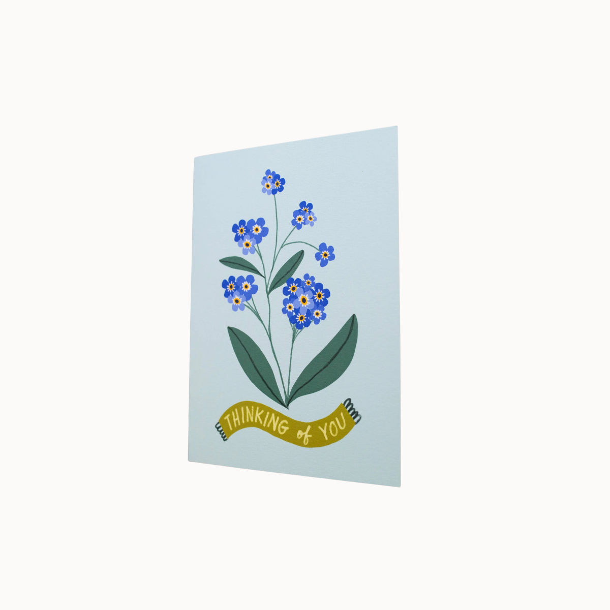 A vertical greeting card featuring a blue forget-me-not flower illustration with green leaves and a yellow banner that reads 'THINKING OF YOU', shown against a plain white background.
