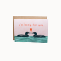 A square greeting card with a kraft envelope, featuring an illustration of two loons facing each other above wavy teal water, with the phrase 'i'm loony for you' in orange handwritten text and a small orange heart between them.