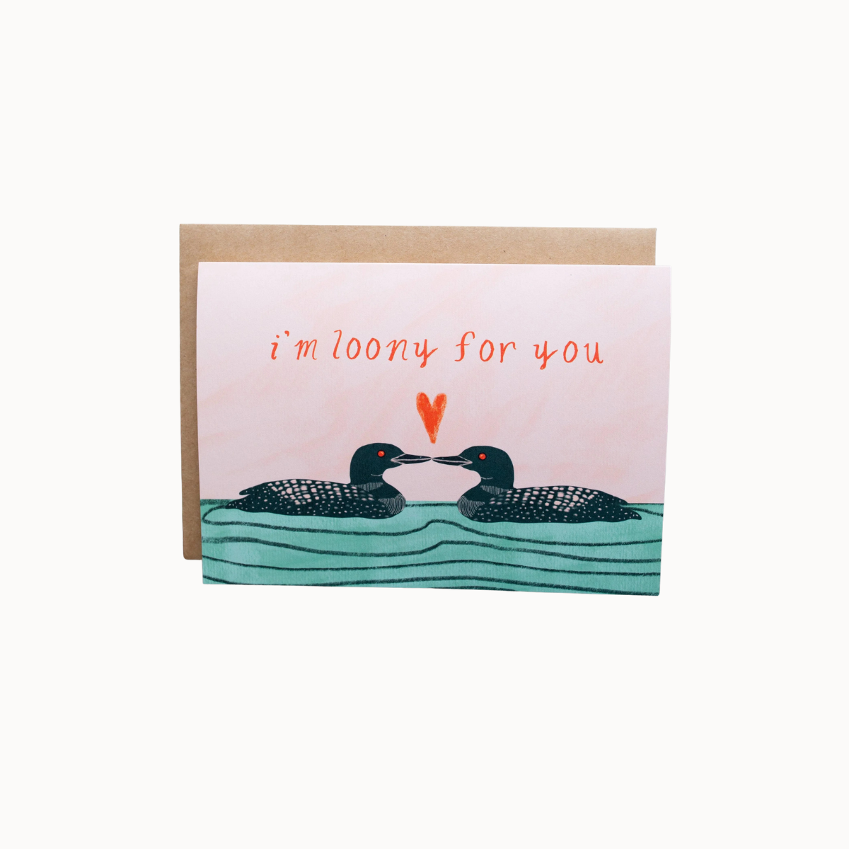 A square greeting card with a kraft envelope, featuring an illustration of two loons facing each other above wavy teal water, with the phrase 'i'm loony for you' in orange handwritten text and a small orange heart between them.
