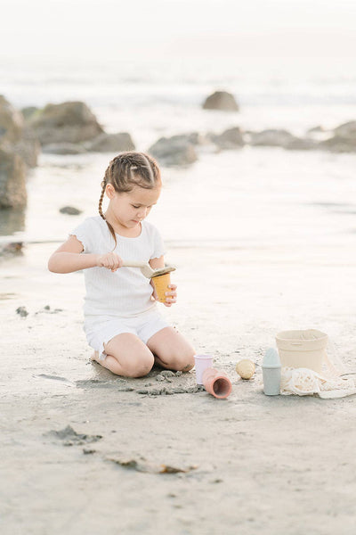 Young girl playing with sand toys on a beach