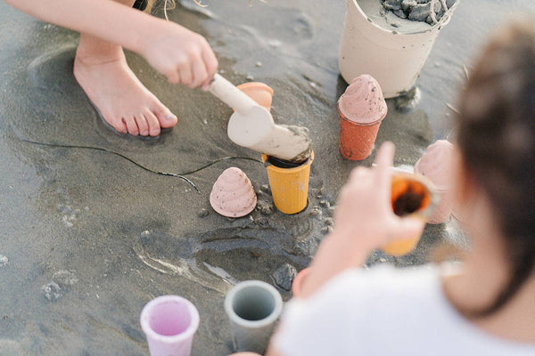 Children playing with colorful sand toys on a sandy surface
