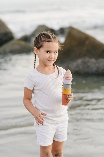 Young girl holding a colorful ice cream cone on a beach
