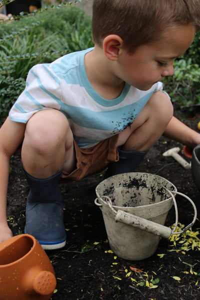 Child in a garden with a pail and watering can
