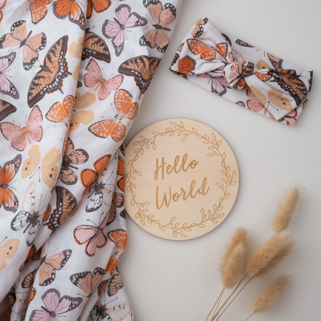 Butterfly-patterned fabric and headband with a 'Hello World' wooden disc on a light background.