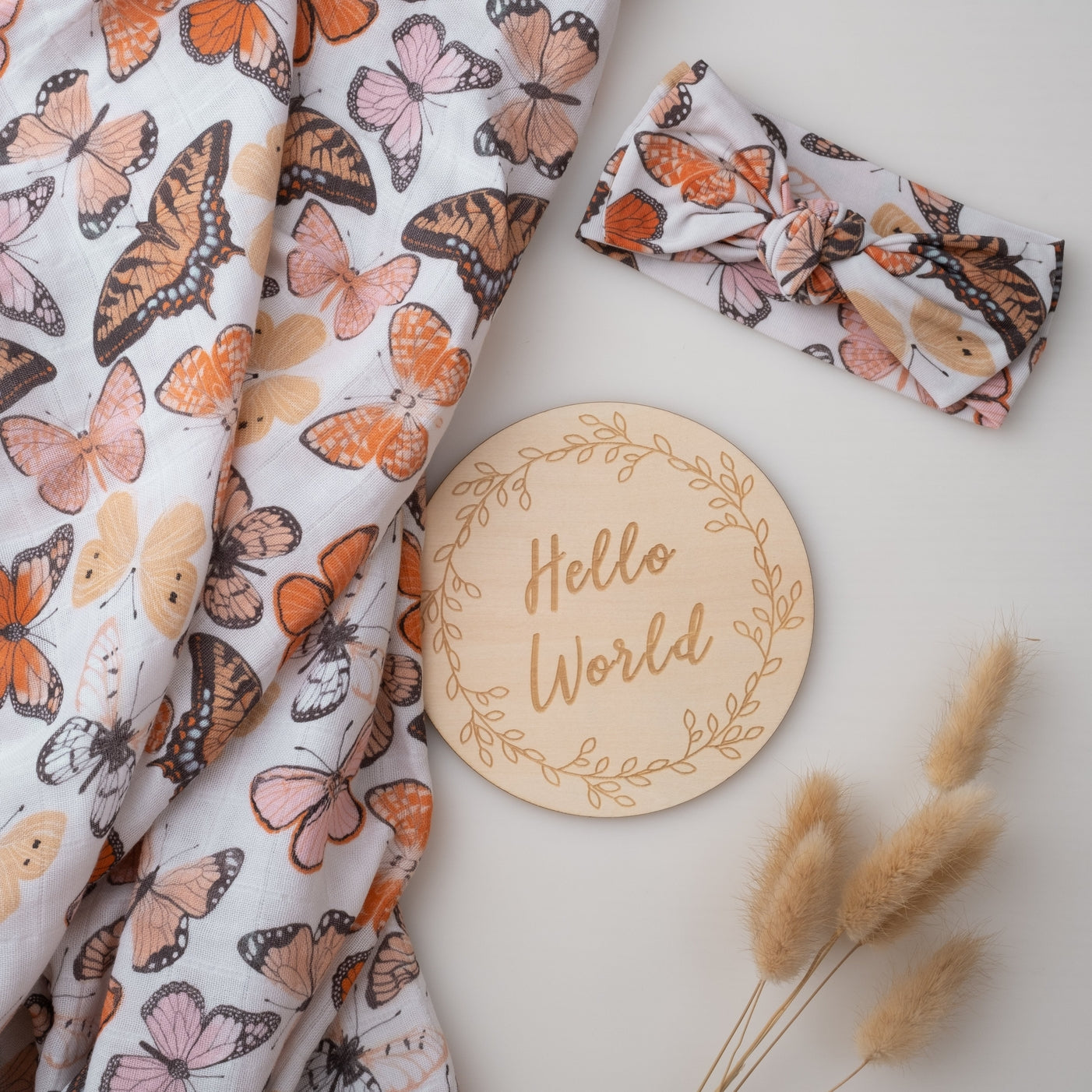 Butterfly-patterned fabric and headband with a 'Hello World' wooden disc on a light background.