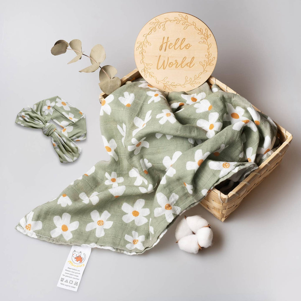 Baby blanket with floral pattern, headband, and 'Hello World' sign on a light gray background