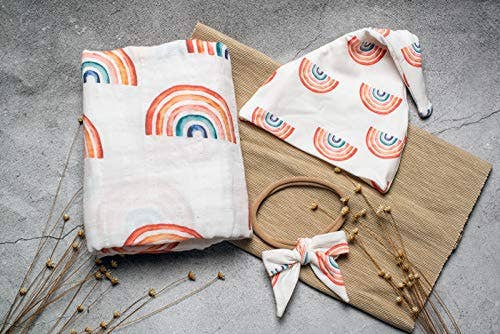 Baby blanket and hat with rainbow pattern on a textured surface