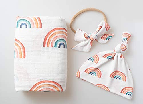 Baby swaddle, headband, and hat set with rainbow pattern on a light background