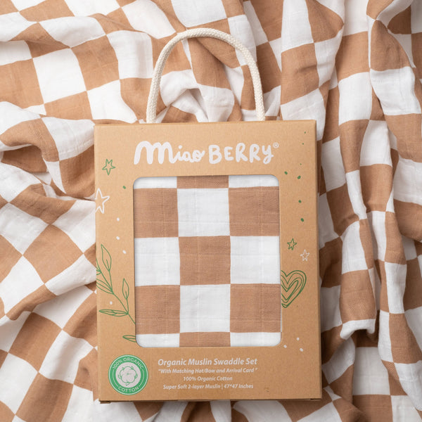 Miss Berry organic muslin swaddle set packaging on a checkered brown and white fabric background