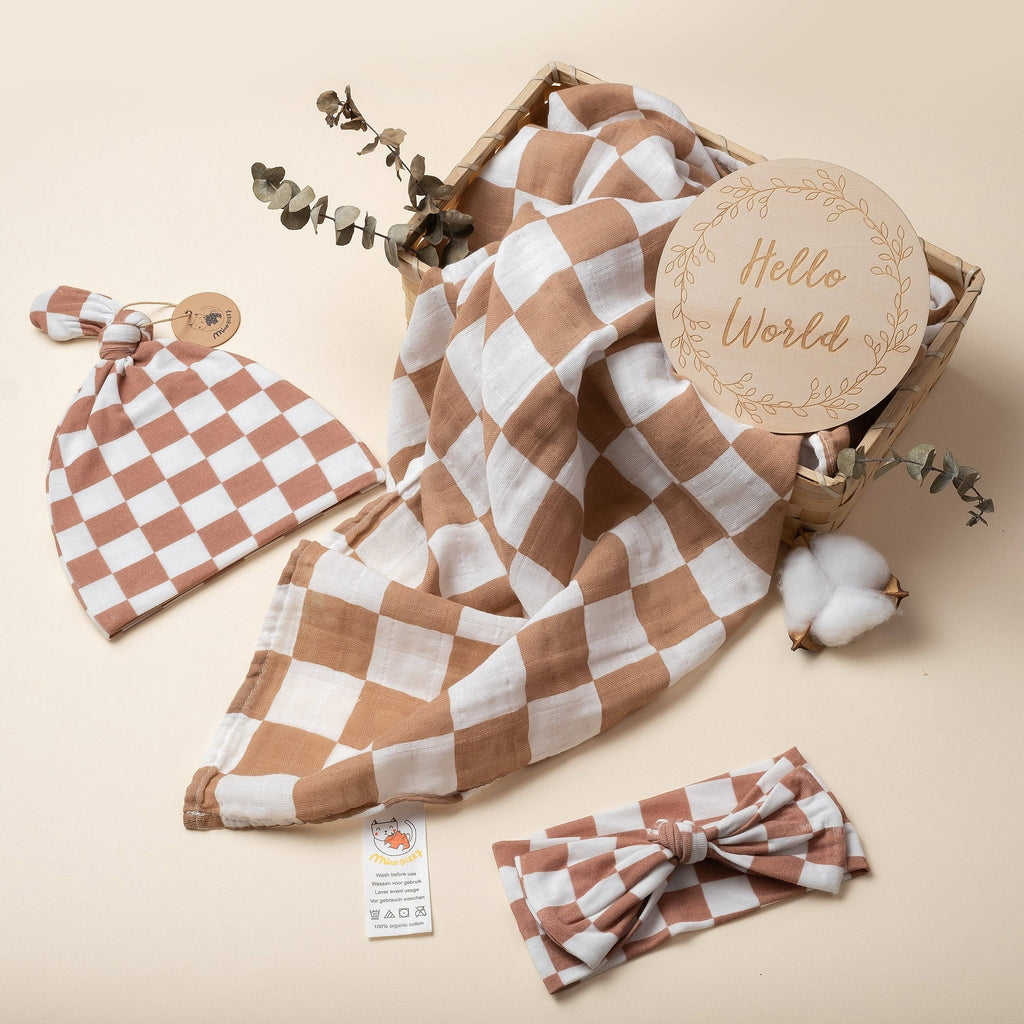 Baby accessories set with checkered blanket, hat, and headband on a beige background