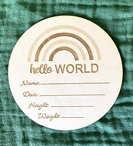 Round wooden card with 'hello WORLD' text and blank lines for personalization on a green textured background.