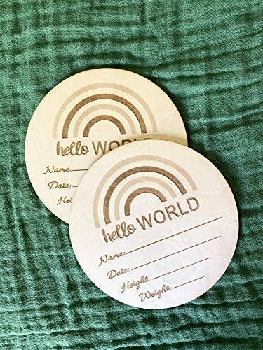 Two round wooden cards with 'hello WORLD' text on a green textured fabric background