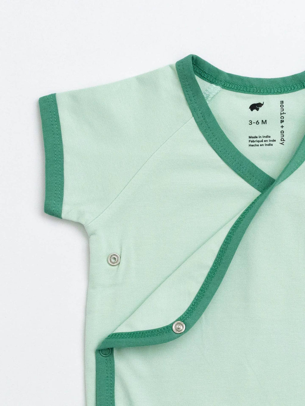 Light green baby outfit with green trim on a white background
