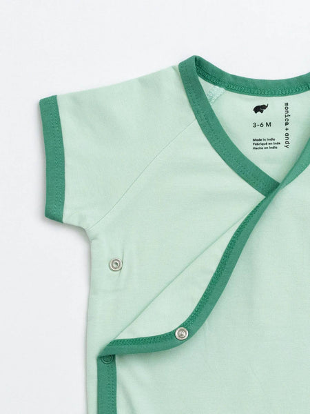 Light green baby outfit with green trim on a white background