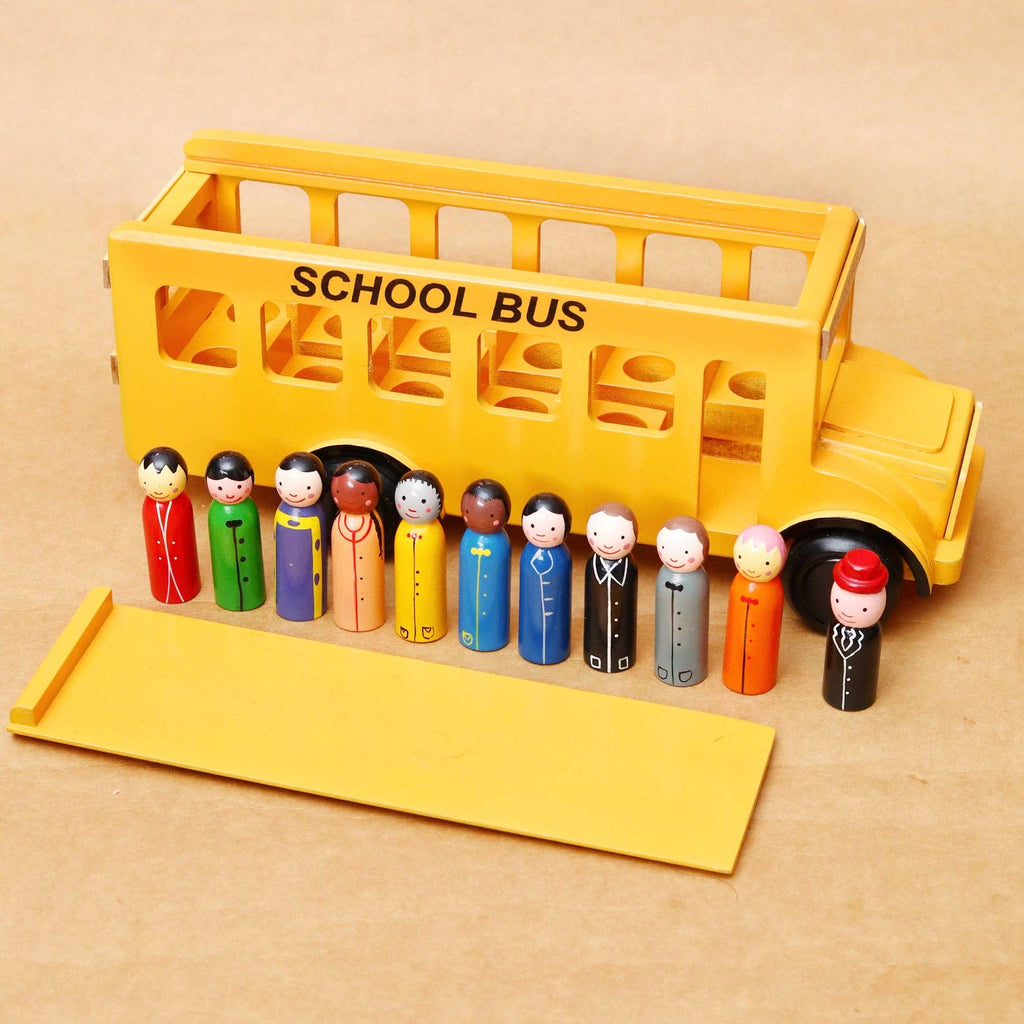 A yellow toy school bus with a removable ramp and ten small wooden passenger figures in different colored outfits lined up on the front, set against a plain beige background.