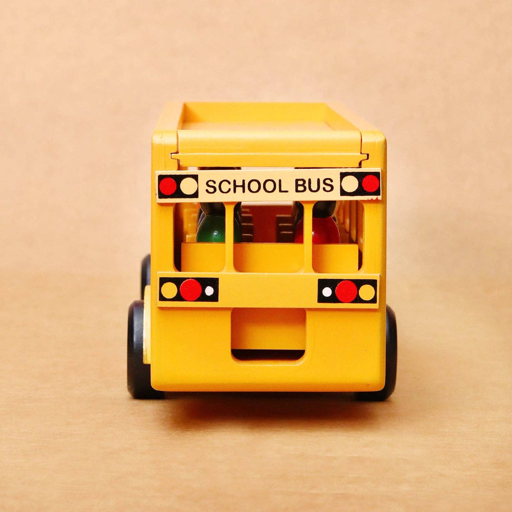 A yellow toy school bus viewed from the back, featuring black wheels and printed red, white, and black taillights, set against a plain beige background.